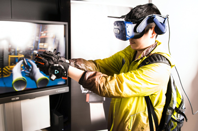 Ein Mann mit Virtual-Reality-Brille und Handschuhen bedient eine Industrie-Anwendung