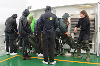 Gruppe von Mitarbeitenden der Seehundstation, die sich Wetterfeste Kleidung und Gummistiefel überziehen