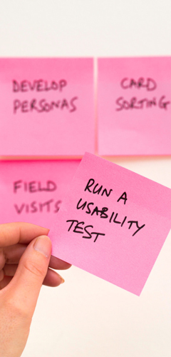Hand hält Post-It mit Text "Run a Usability Test"