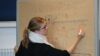 junge Frau schreibt etwas an Flipchart mit der Überschrift "Sommerfest".